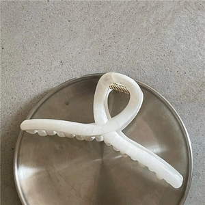 Dettaglio della grande pinza per capelli con trama marmo bianco e molla metallica
