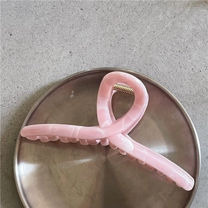 Dettaglio di una pinza per capelli con motivo in marmo rosa e molla in metallo dorato