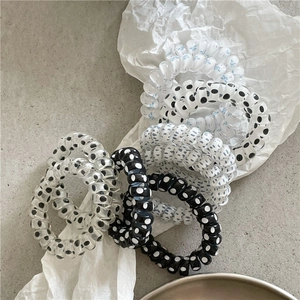 Detailed view of polka dot spiral hair ties set on white textured art paper