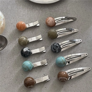 Close-up of marble pattern resin beads and glossy metal BB clips in five colors