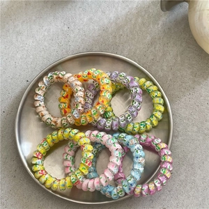 Close-up of colorful floral spiral telephone wire hair ties in a metal tray