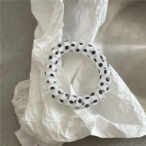 Close-up of spiral telephone wire hair tie with black and white polka dots on white paper