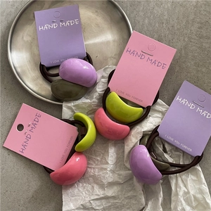 Pastel semi-round ponytail holders set on a metal tray with stylish decorative props