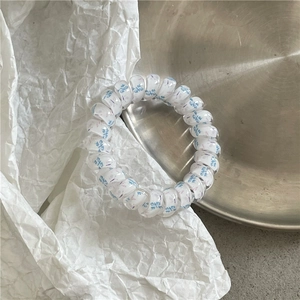 Detail of spiral hair tie with blue butterfly print on a silver metal tray