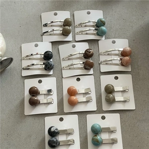 Close-up of marble pattern planet beads on metallic hair clips in various colors