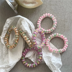 Five colorful spring-themed spiral hair ties with floral patterns on stone surface