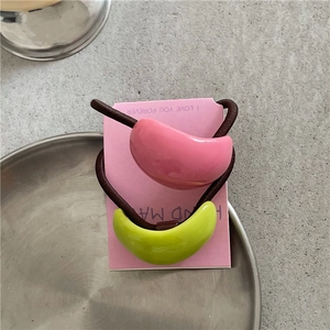 Detail of pink and lime green resin ponytail holders set on a display card and metal tray