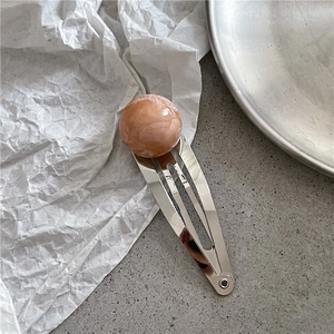 Detailed macro view of an amber marble resin bead set on a polished silver metal hair clip