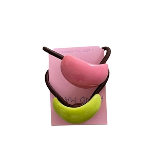 Set of two colorful semi-circular ponytail holders in pink and green on a gift card