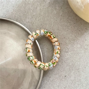 Close-up of a colorful spiral hair tie with graffiti patterns on a metallic plate