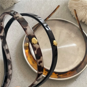 Detail of tortoiseshell and black headbands with gold metallic accents on a tray