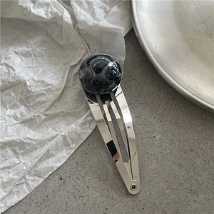 Detailed view of silver BB hair clip with marble pattern resin bead on modern grey surface