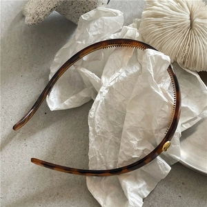 Detailed view of leopard resin headband with gold metal studs and non-slip inner teeth