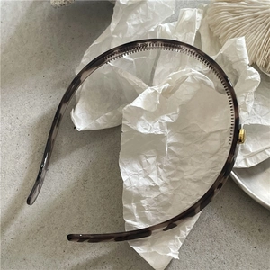 Detail of tortoiseshell headband showing anti-slip teeth and golden metal accent decor