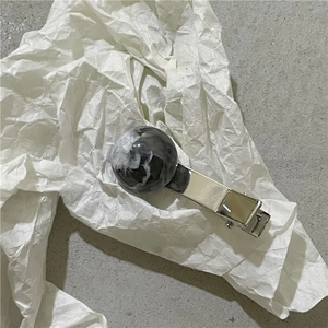Detailed close-up of marble pattern planet ball hair clip with polished silver metal base