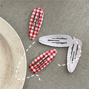 Détail de quatre barrettes BB à motif de carreaux et bords ondulés sur un plateau