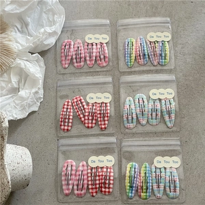 Détail de 6 packs de barrettes à cheveux à carreaux dans des pochettes zippées