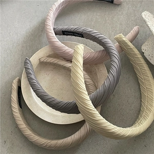 Serre-têtes plissés en tissu aux tons pastels disposés sur un plateau en céramique