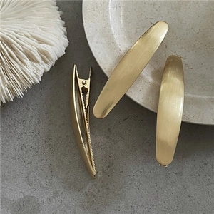 Set di tre fermagli per capelli ovali in metallo spazzolato oro opaco su fondo in pietra