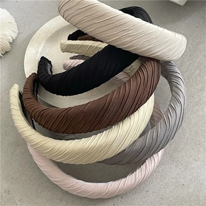 Détail de serre-têtes en tissu plissé montrant l'étiquette faite main et le rembourrage