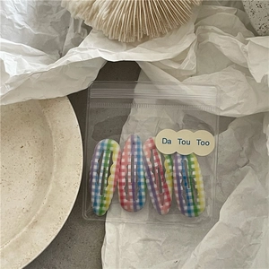 Détail de quatre pinces à cheveux à carreaux colorés dans un emballage transparent