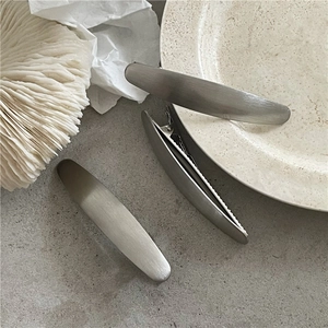 Dettaglio di fermagli per capelli in metallo spazzolato argento opaco con design ovale set da 3