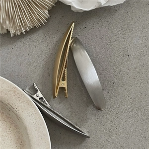 Dettaglio delle clip per capelli in metallo spazzolato opaco con presa a becco d'anatra