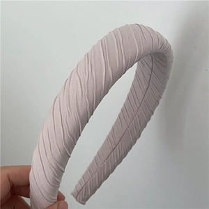 Détail de la texture d'un serre-tête en tissu plissé rose clair avec rembourrage épais
