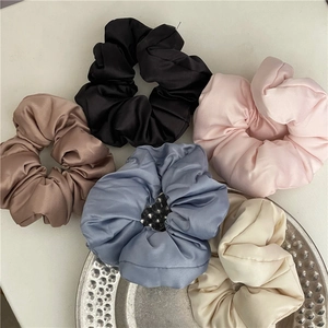 Vista dettagliata di cinque elastici scrunchie in raso nei colori nero, rosa, blu e beige