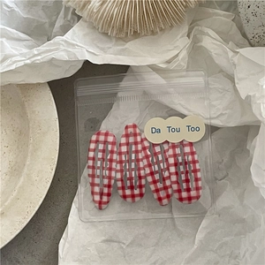 Détail de barrettes à motif vichy rouge et blanc dans un emballage transparent
