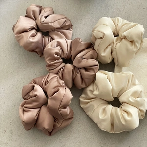 Texture dettagliata di elastici per capelli in raso marrone e beige su superficie grigia