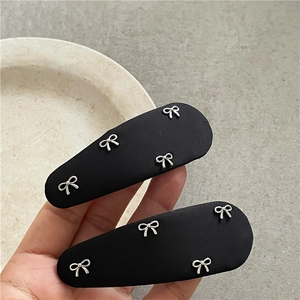 Détails de deux barrettes à cheveux en tissu noir avec des nœuds en métal argenté
