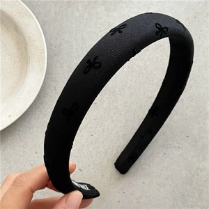 Dettaglio del cerchietto in tessuto nero con fiocchi ricamati ed etichetta handmade