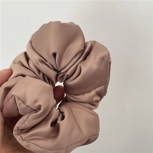 Dettaglio di un grande elastico scrunchie in raso rosa cipria con lucentezza e pieghe