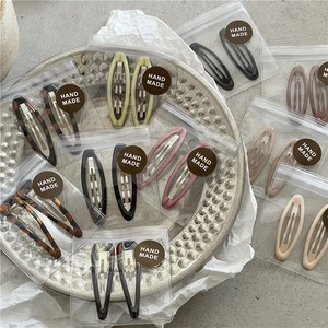 Close-up of assorted tortoiseshell and matte finish oval hollow BB hair clips on a silver tray