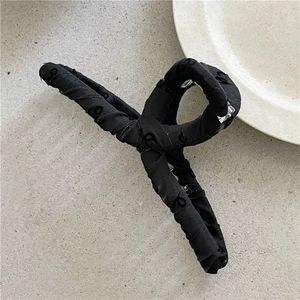 Dettaglio di un grande fermaglio per capelli in tessuto nero ricamato per acconciature