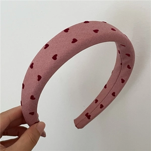 Detail of a pink padded sponge headband featuring a small red heart pattern and fabric texture