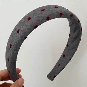 Close-up of grey padded headband with red heart prints and soft fabric texture