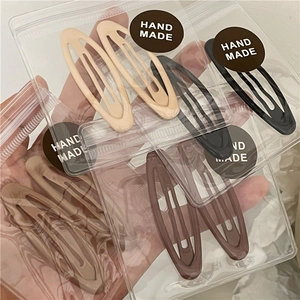 Detail of oval metal BB clips in earth tones inside transparent hand made packaging