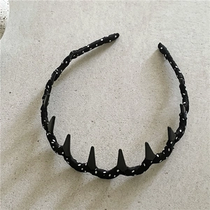 Detail of black polka dot headband featuring seven edgy black matte triangular spikes