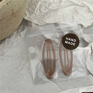 Pair of oval mocha brown metal hair clips in handmade packaging with kraft texture