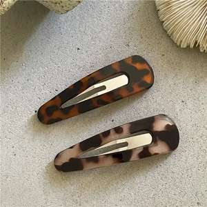 Retro leopard print and tortoiseshell hair clips set on a textured stone surface
