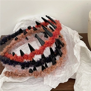 Detailed view of colorful plush headbands with edgy black spikes on white paper
