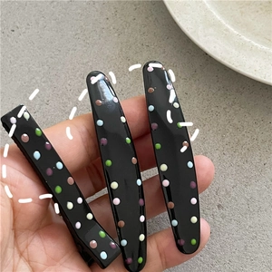 Close-up of black hair clips with colorful polka dots, including square and oval shapes