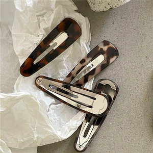 Macro detail of tortoiseshell leopard print hair clips with silver metal snap fasteners