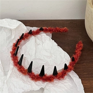 Close-up of plush fuzzy headband featuring decorative black monster teeth spikes