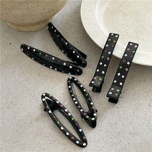Detailed view of colorful polka dot hair clips on a minimalist grey textured background