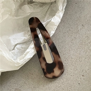 Close-up of tortoise shell leopard print hair clip on minimalist stone background