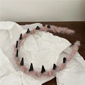 Detail view of plush headband with pink fur and black punk spikes on white paper