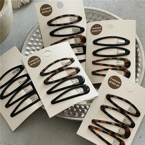 Macro view of leopard print and solid black teardrop hair clips on a jewelry display card